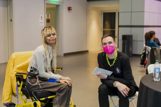 Event photograph with two Altered Access participants seated and smiling at the camera.