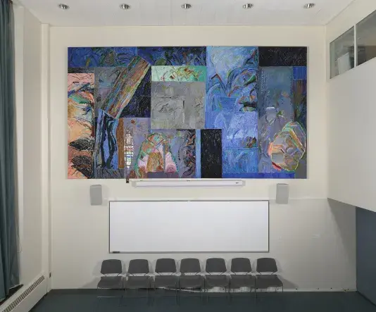 Large abstract painting comprised of a collection of predominantly blue and black patterned squares hanging on a cream colored wall above a row of chairs. 