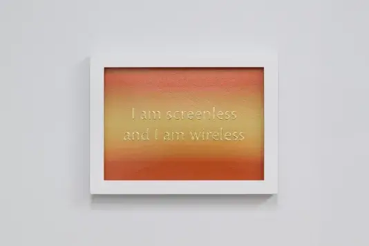 Bright orange and yellow ombre with two line of shimmery gold text and a white frame. The text reads "I am screenless and I am wireless"