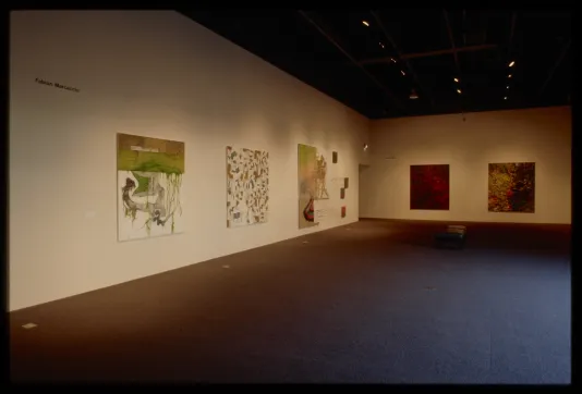 Five large abstract paintings, three with earthen colors on white background and two red and black splattered, hang on adjacent walls.