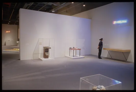 Viewer looking at neon sign in the distance of a gallery space. 