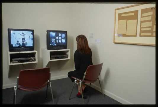 Woman seated at desk looking at computer screen with another chair and desk next to her. 