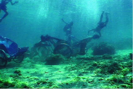 Video still of men plunging into Vietnam’s IndoChina Sea, where passengerless cyclos sit underwater